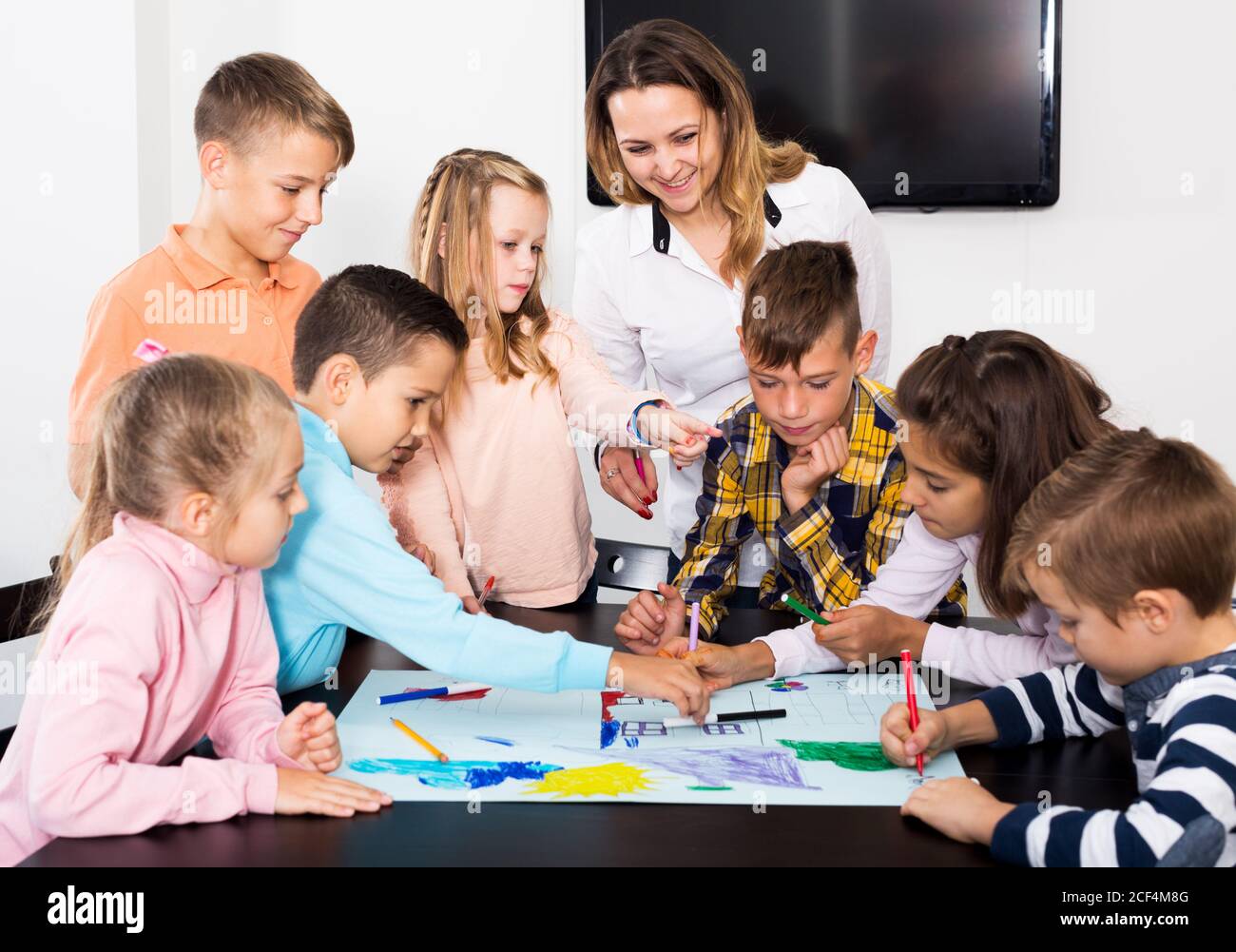 Portrait smiling team of elementary age children and teacher drawing on ...
