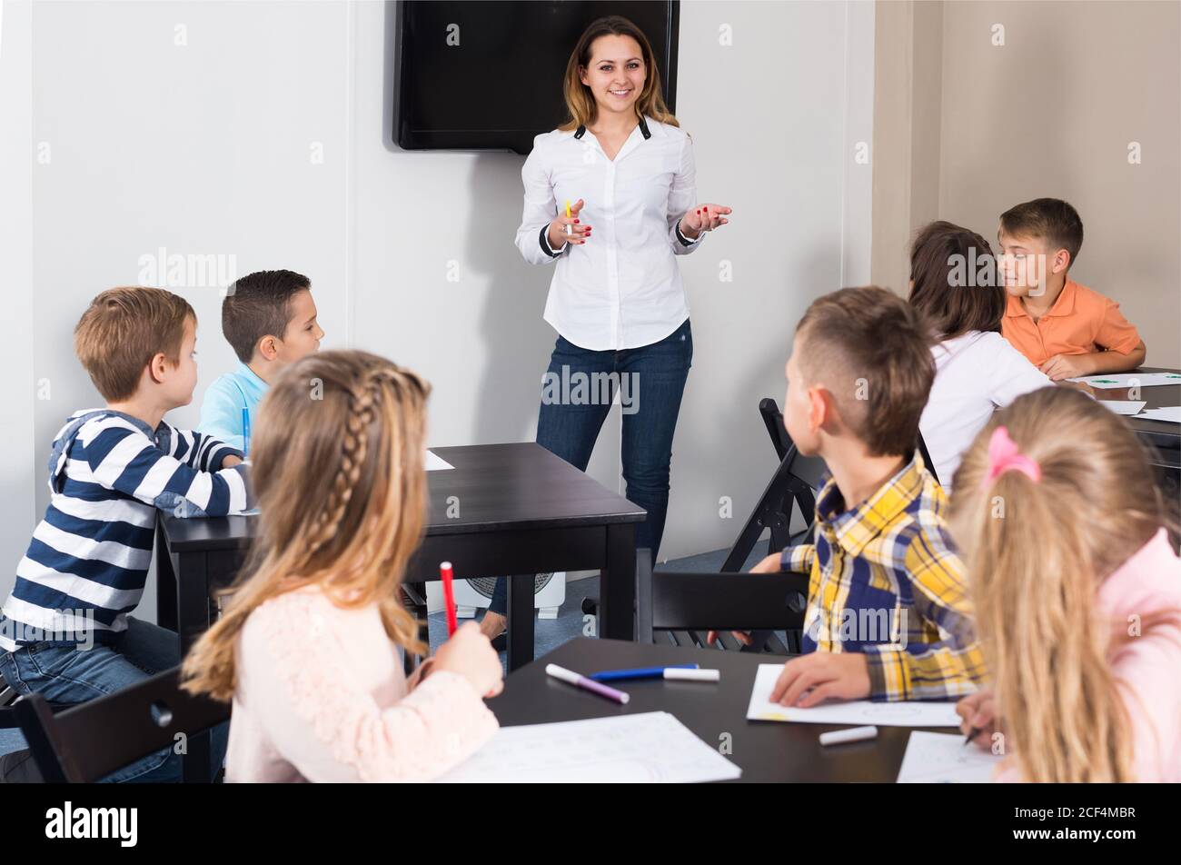 Happy teacher and elementary age children drawing at classroom Stock ...