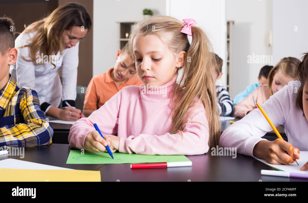 Girl and children in elementary age at drawing lesson together Stock ...