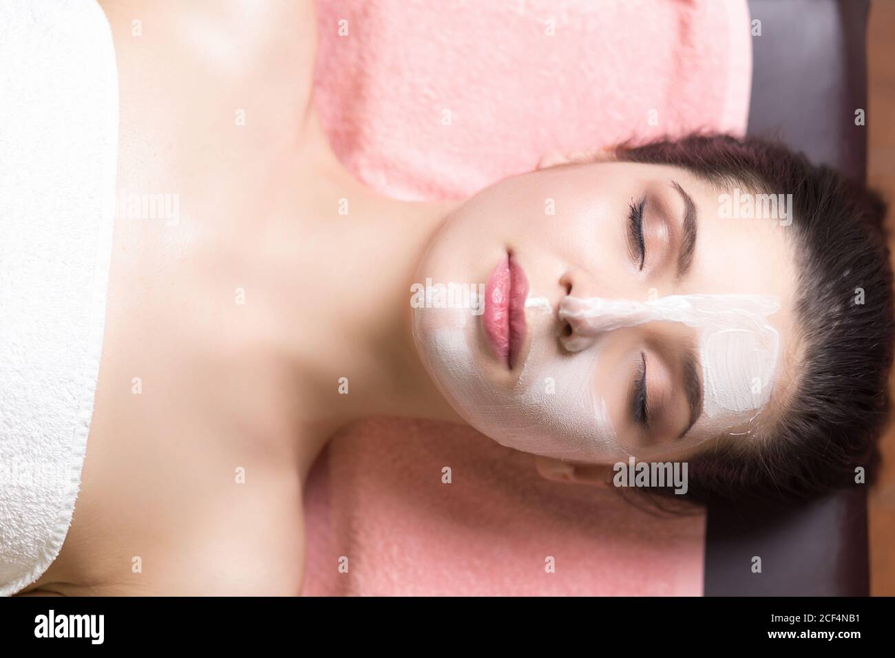 Spa Woman applying Facial cleansing Mask. Beauty Treatments Stock Photo