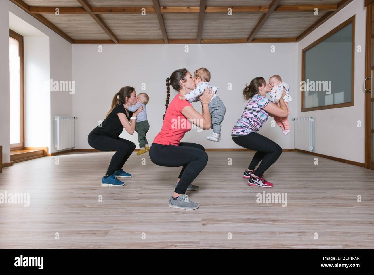 Mothers lifting babies in gym Stock Photo Alamy