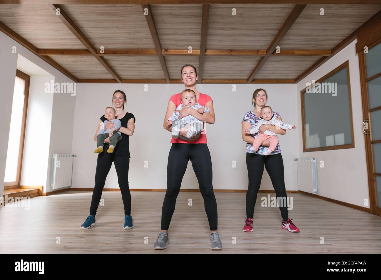 Mothers lifting babies in gym Stock Photo Alamy