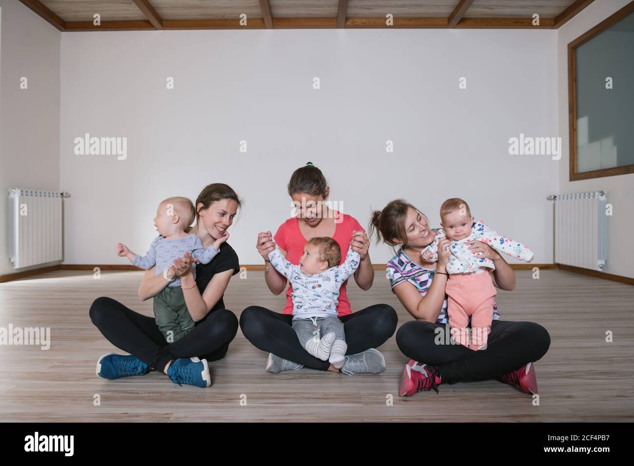 Mothers lifting babies in gym Stock Photo Alamy