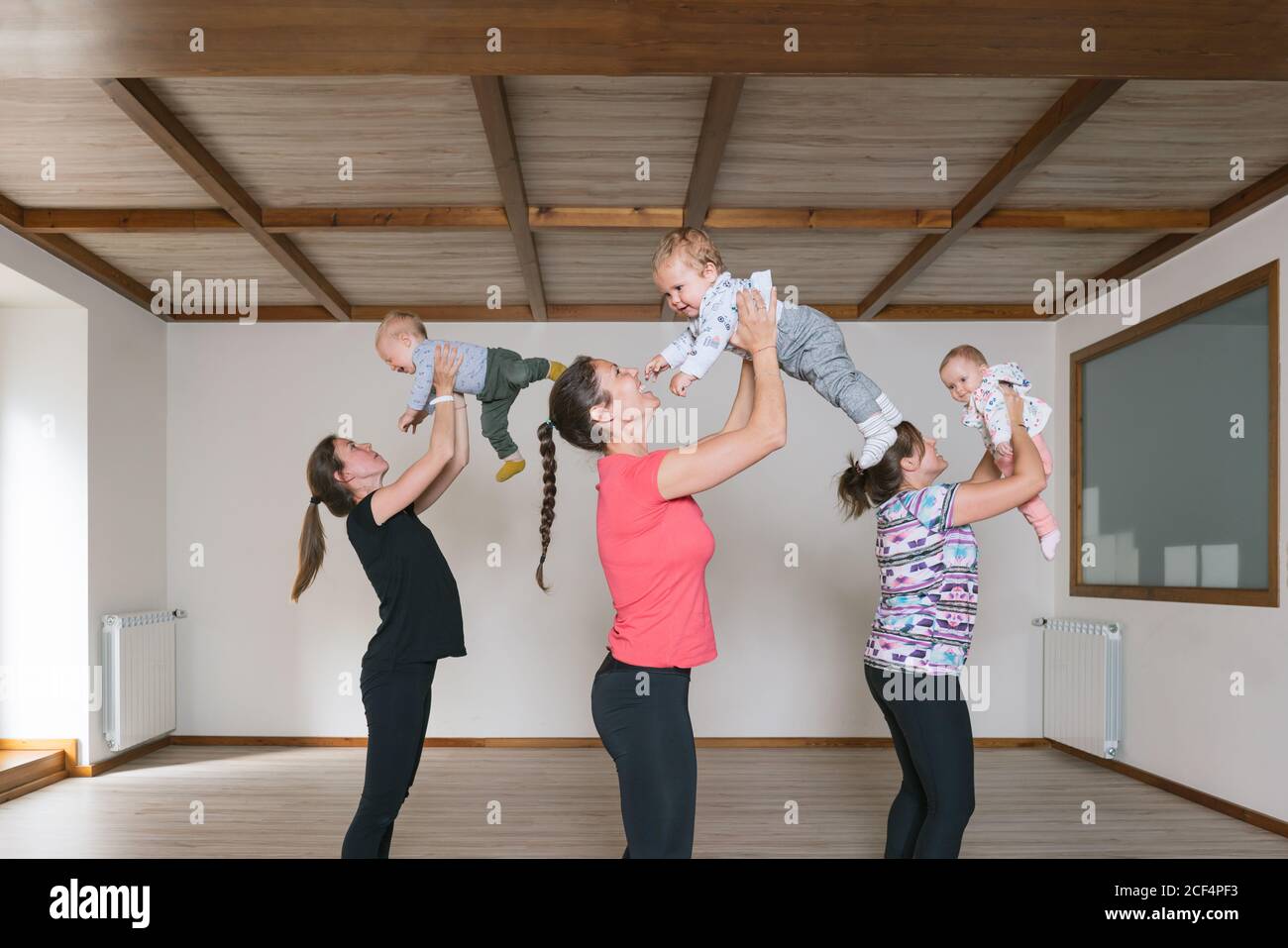 Mothers lifting babies in gym Stock Photo Alamy