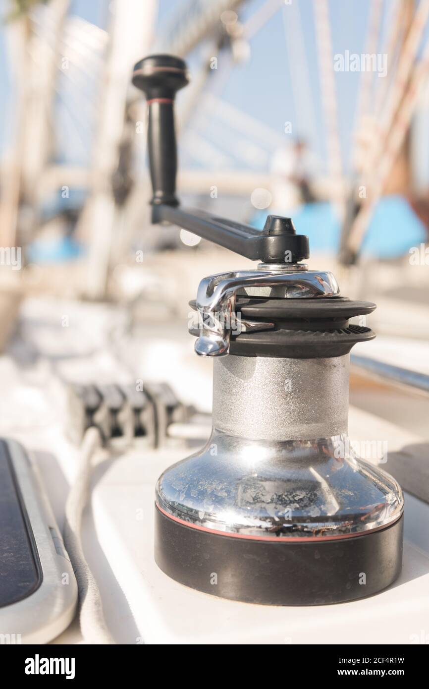 Winch with handle for hoisting rope on boat in sunny day on blurred