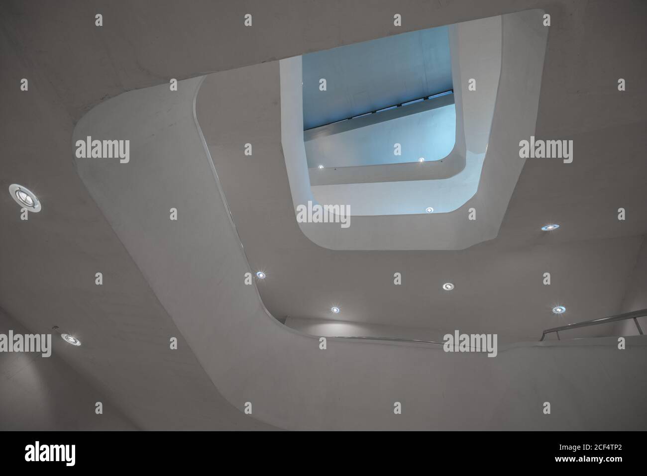 From below of perspective contemporary illuminated stairway in white color going spiral Stock Photo