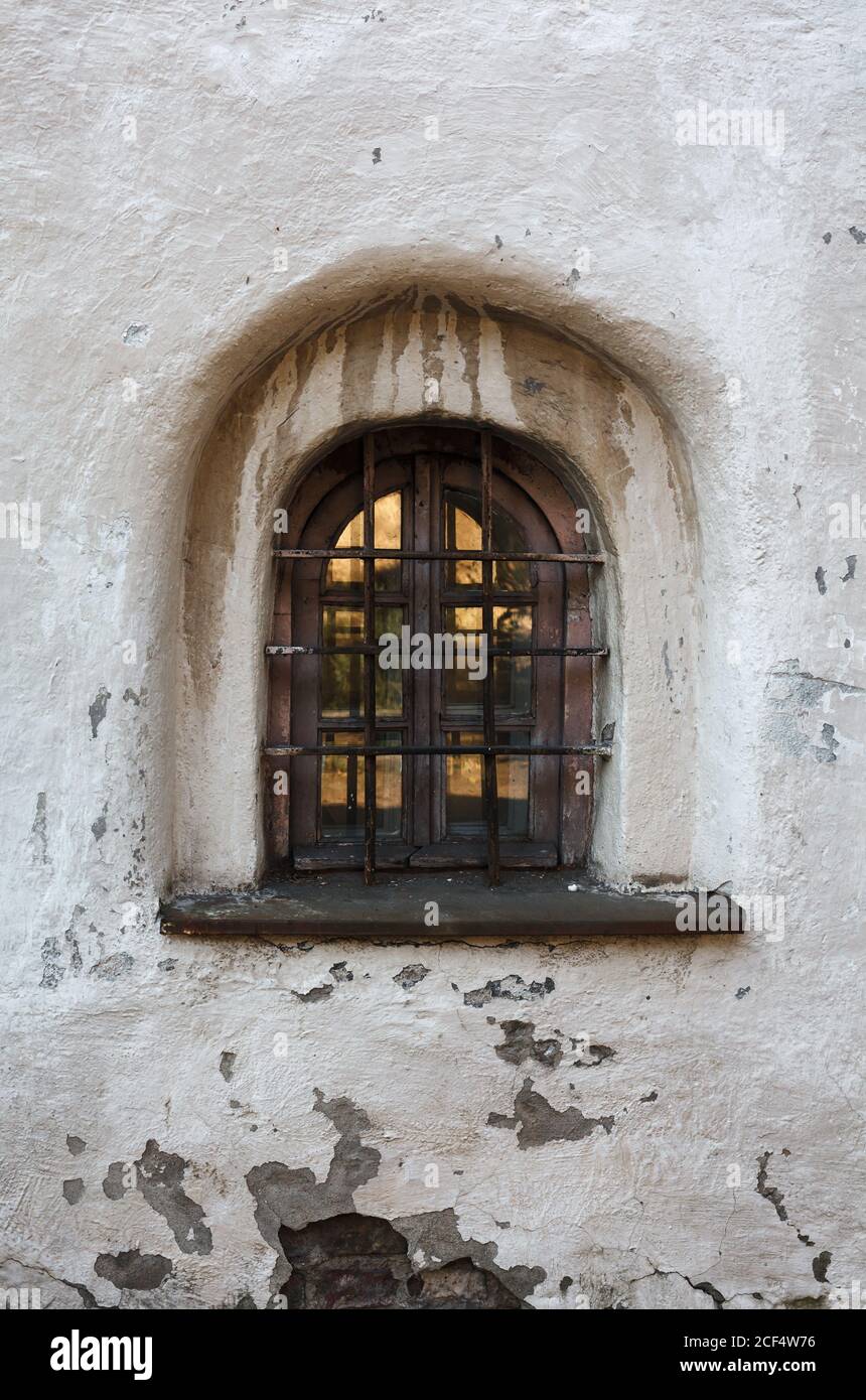 Tiny caged old window in bleached monastery wall, medieval abbey Stock Photo