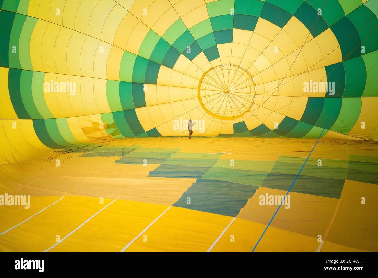 unrecognizable man checking condition of large green and yellow air balloon while standing inside and conducting maintenance Stock Photo