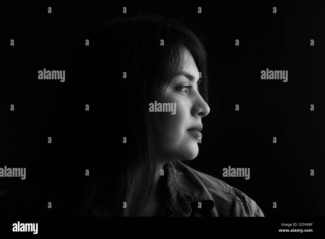 side view of dark portrait of a latin woman on black background, black and white Stock Photo