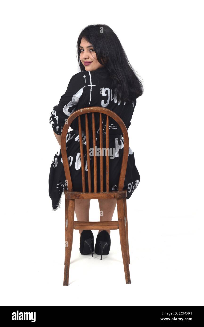 rear view latin woman with dress and high heels sitting on chair on