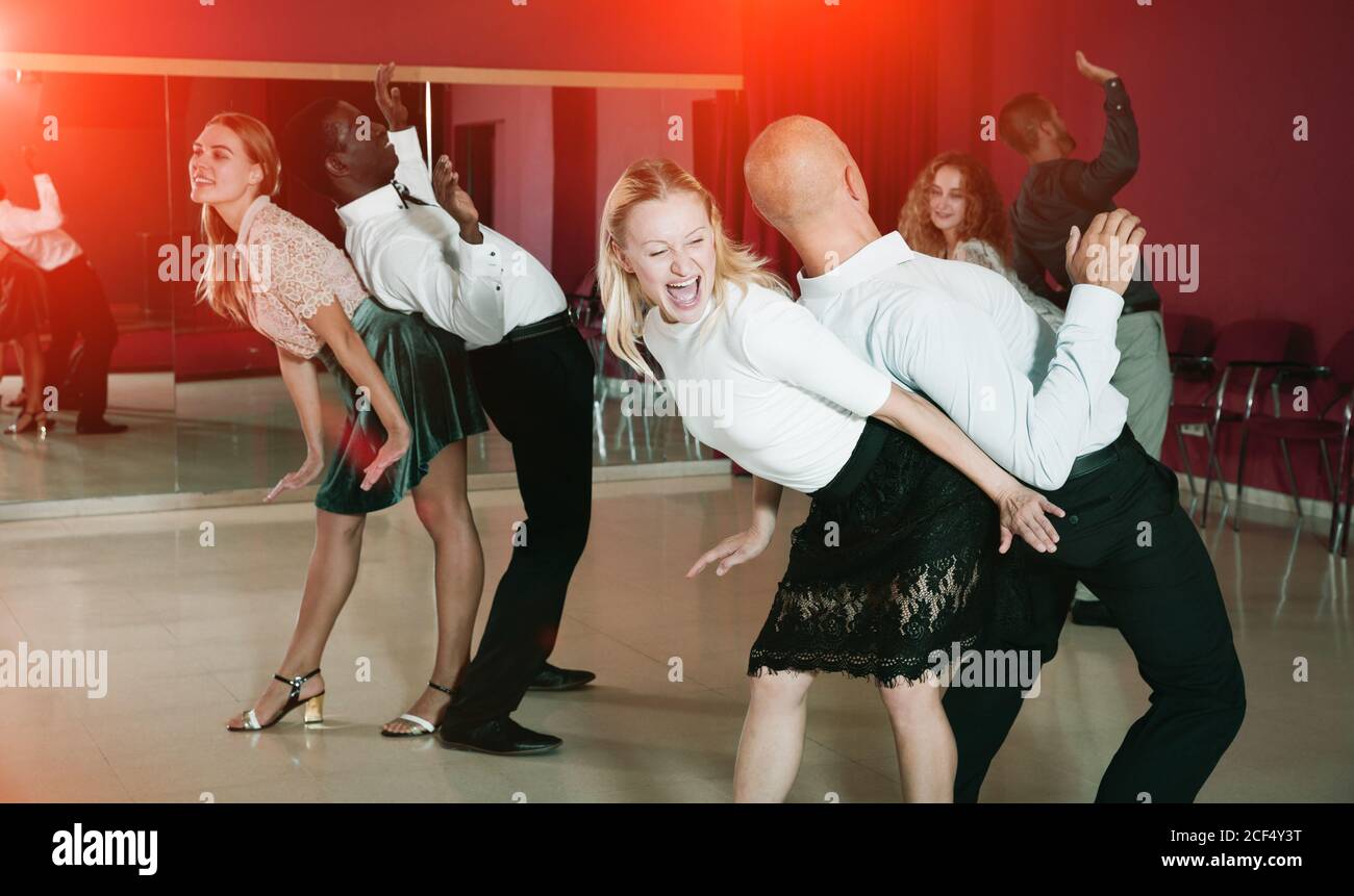 Young smiling people practicing vigorous jive movements in dance class Stock Photo