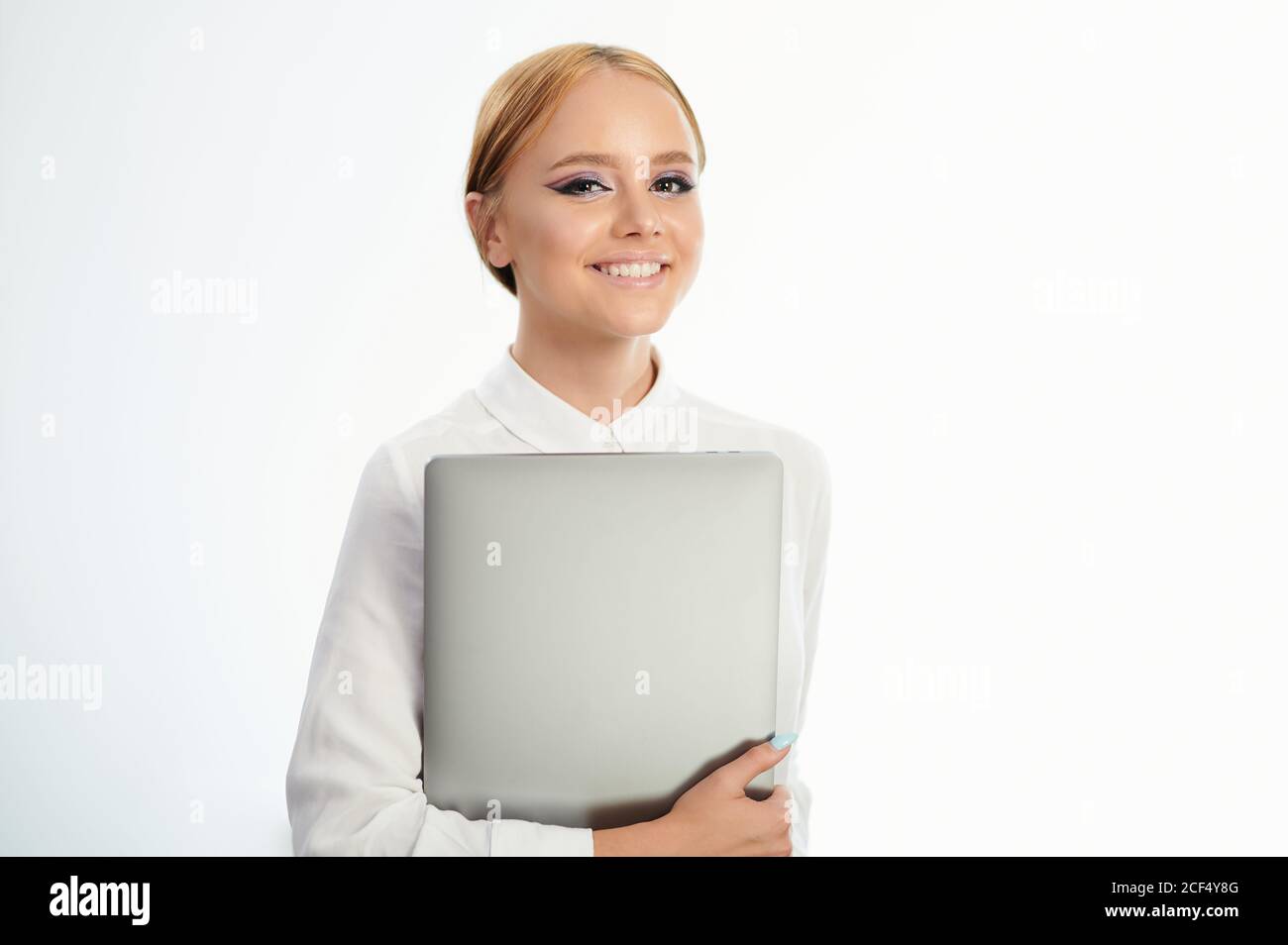 Portrait of girl smiling and holding laptop isolated on white studio ...