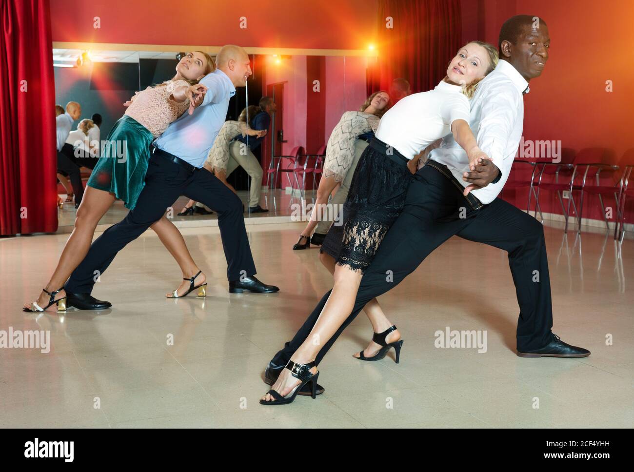 Young smiling people practicing passionate samba in dance class Stock Photo