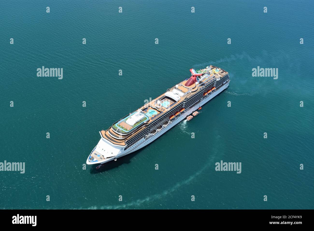 The Carnival Spirit anchored off the coast of Port Denarau in Fiji.  The cruise ship is seen during a tendering operation.  Green blue water. Stock Photo