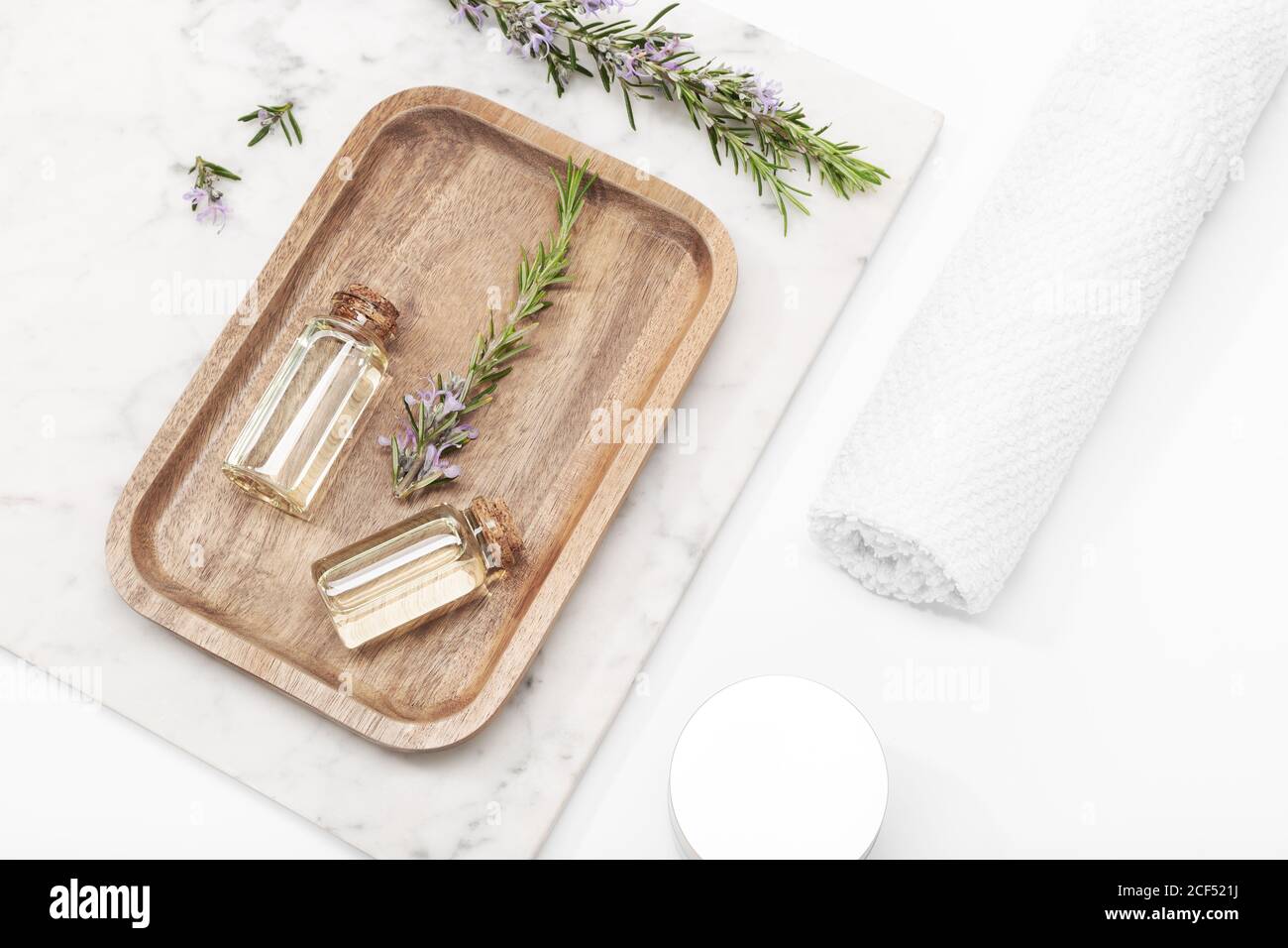 Rosemary essential oil in glass bottle on wooden tray. Salvia Rosmarinus oil Stock Photo
