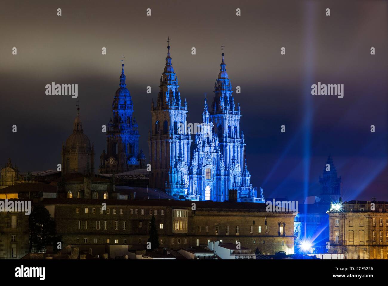 Towers of Santiago de Compostela Cathedral with blue light surrounded with buildings at night Stock Photo