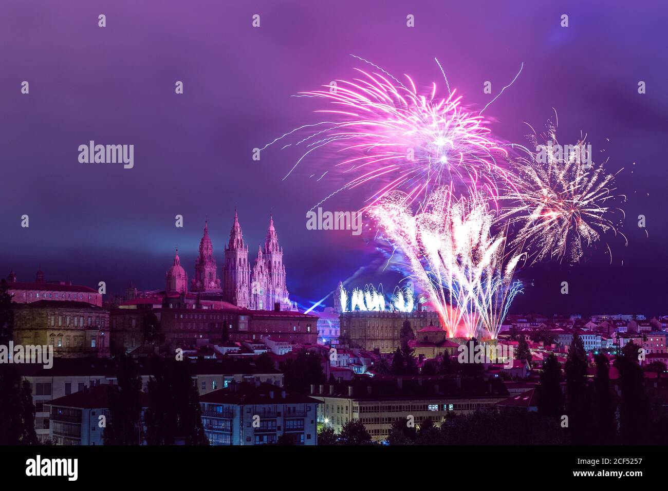 Distant colourful firework next to Santiago de Compostela Cathedral towers in purple evening sly Stock Photo