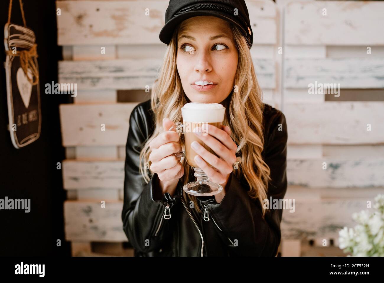 Long haired trendy Woman holding glass of delicious foamy coffee