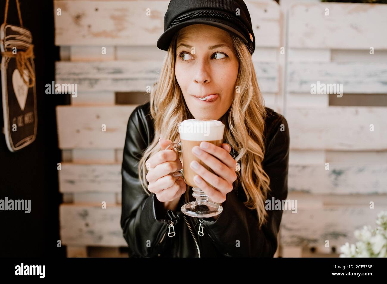 Long haired trendy Woman holding glass of delicious foamy coffee