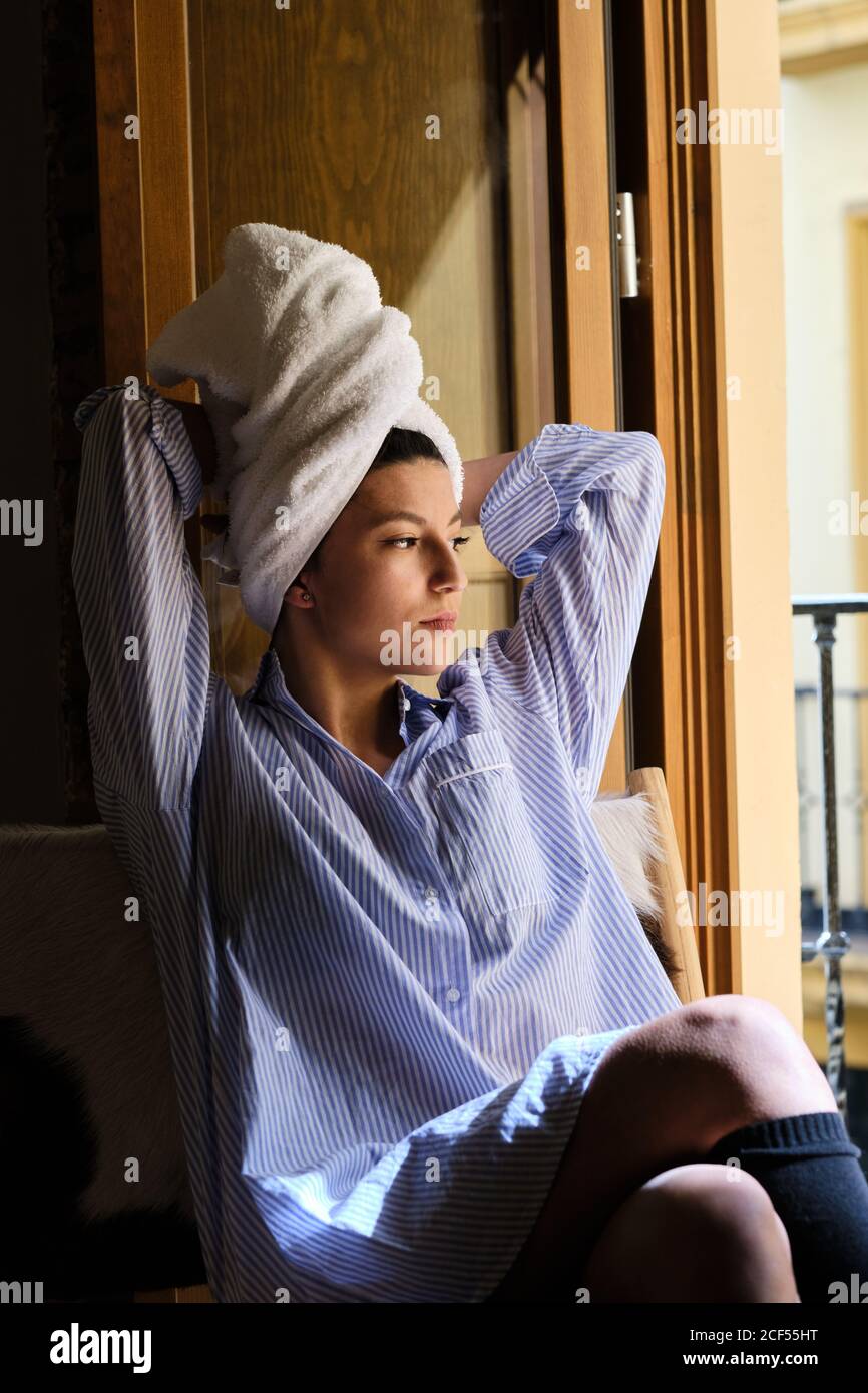 Pensive Woman in casual outfit with towel on wet hair sitting with