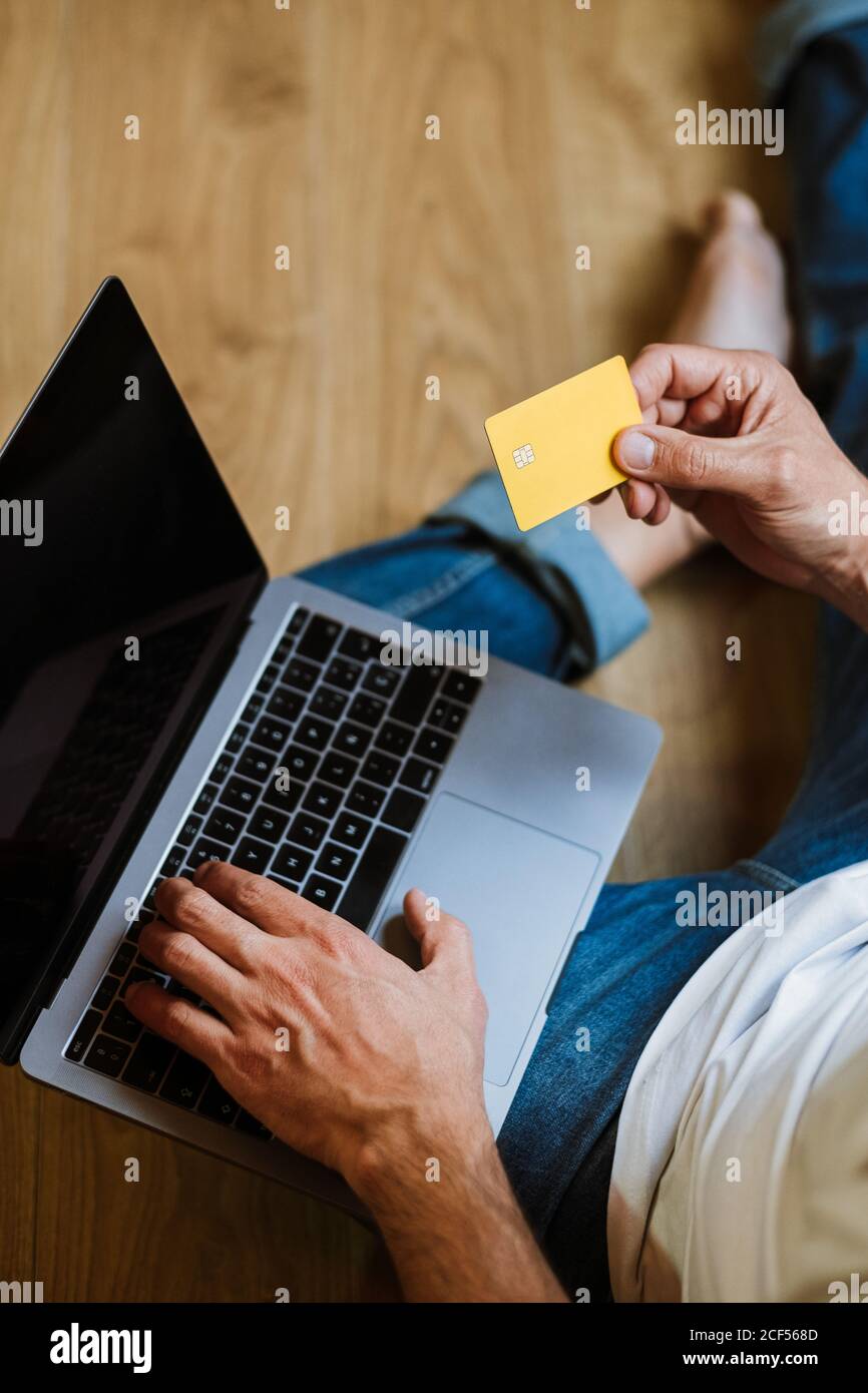 From Above Anonymous Man With Credit Card Sitting On Floor And Using Laptop To Make Online Purchases At Home Stock Photo Alamy