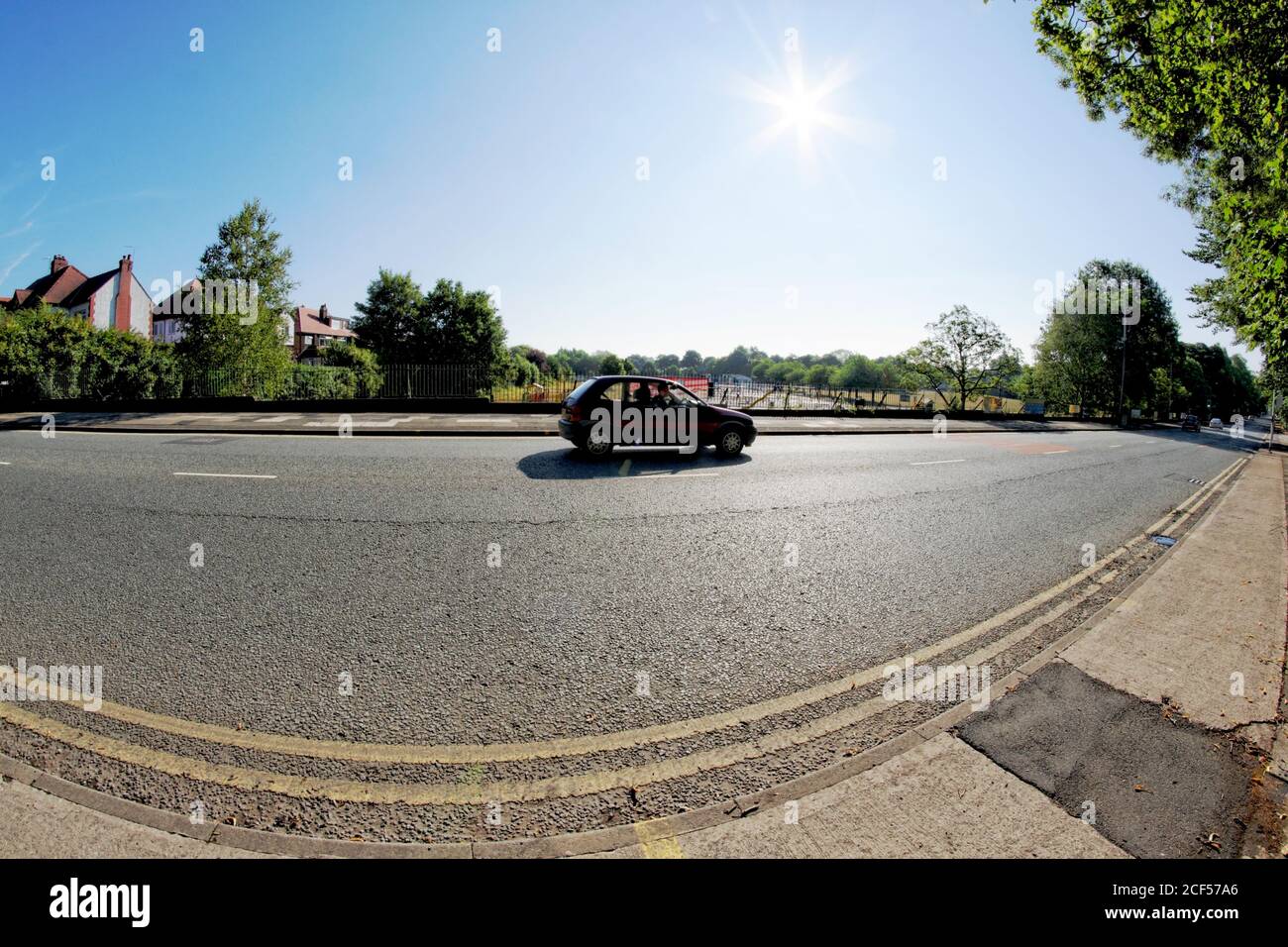 Fisheye lens view of a passing car on the long and straight Bury New Road in Prestwich, Manchester, taken against the light (contre-jour) Stock Photo