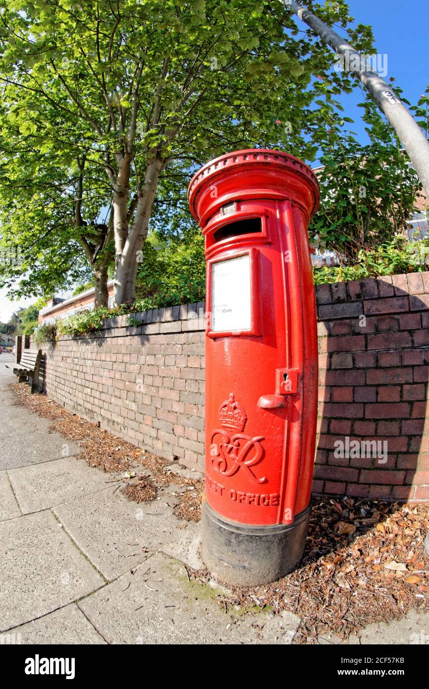 A bright red, traditional UK Royal Mail (formerly the Post Office)  postbox located in Prestwich, Bury, Greater Manchester Stock Photo