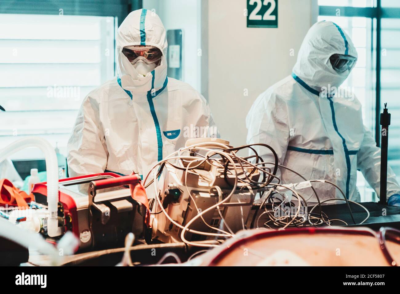 Unrecognizable professional doctors in protective uniforms and masks taking care of patient with viral infection while standing in operating room in modern hospital Stock Photo