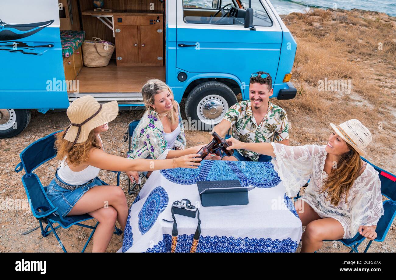 Smiling cheerful friends raising bottles of drink and clinking for holiday in car Stock Photo