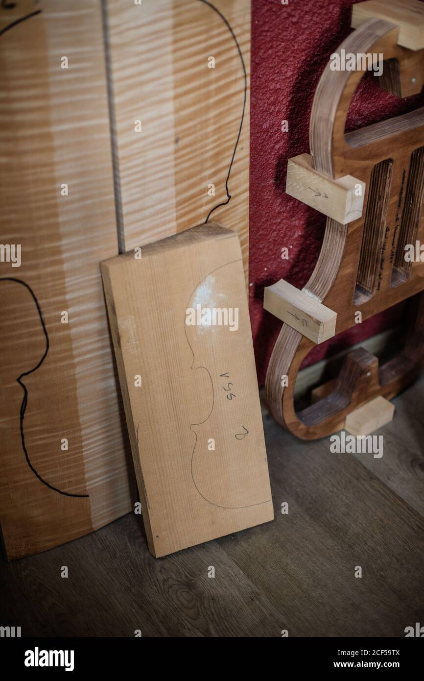 High angle of wooden boards with marking of details of violin instruments placed on floor beside wall in modern workroom Stock Photo