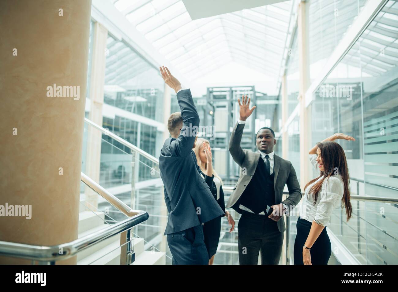 Successful business team is giving high five and smiling while standing ...