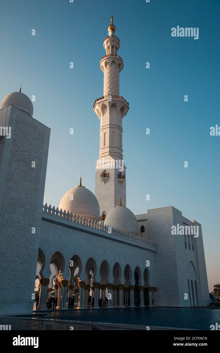 Amazing huge mosque with high tower near pool and blue sky in Abu Dhabi, United Arab Emirates Stock Photo