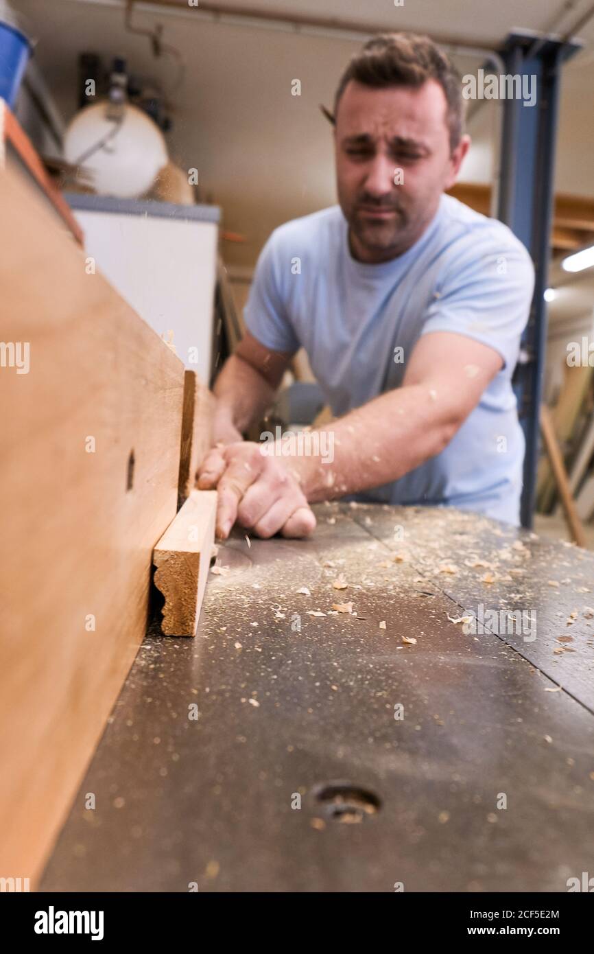 Low angle of focused carpenter milling timber while crafting detail ...