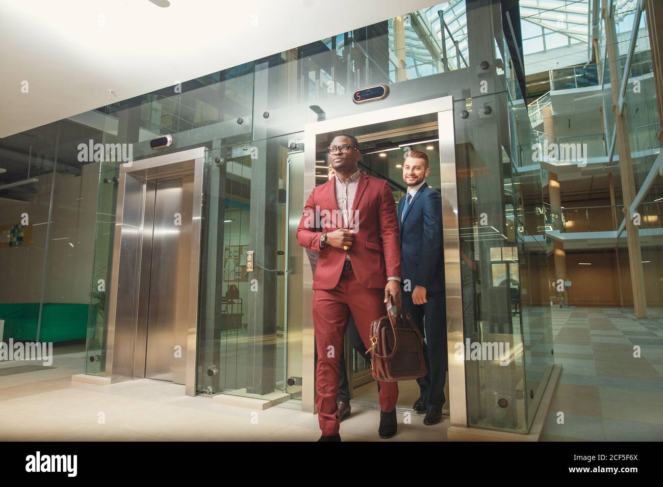 business group comes out from glass Elevator Stock Photo