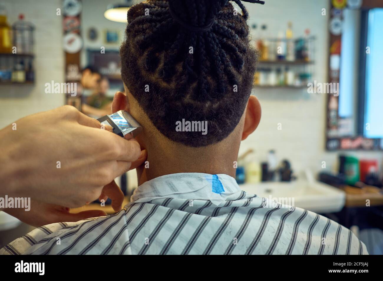 Crop view from behind of anonymous hairstylist doing a modern haircut ...