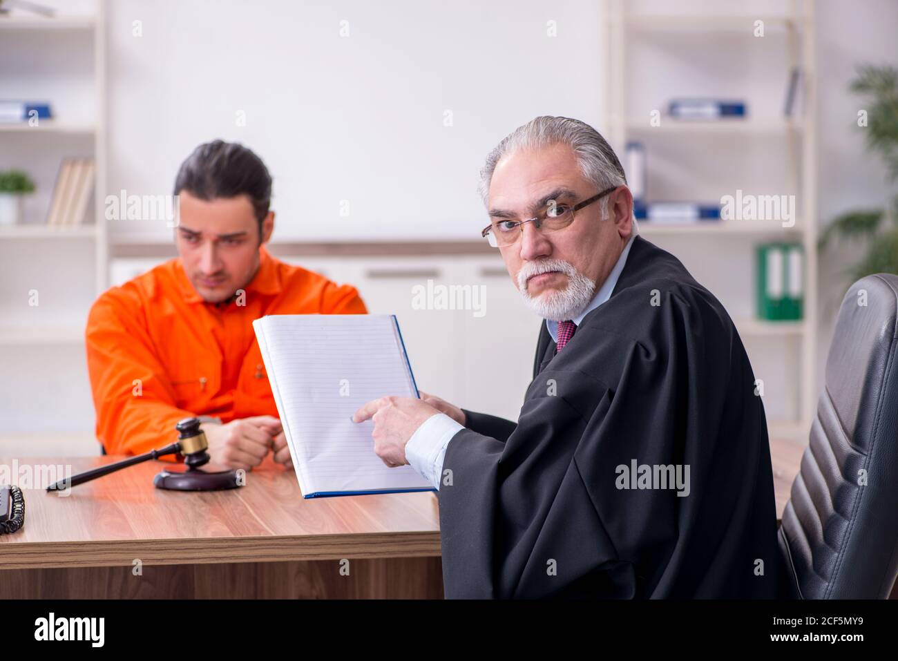 Old judge meeting with young captive in courthouse Stock Photo
