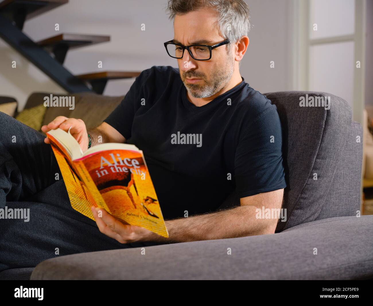 man reading a relaxed book alone on the sofa in the living room at home Stock Photo