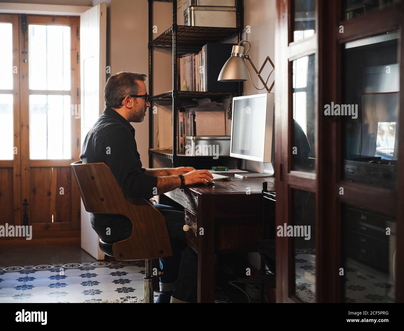 man working at home desk with computer via internet Stock Photo