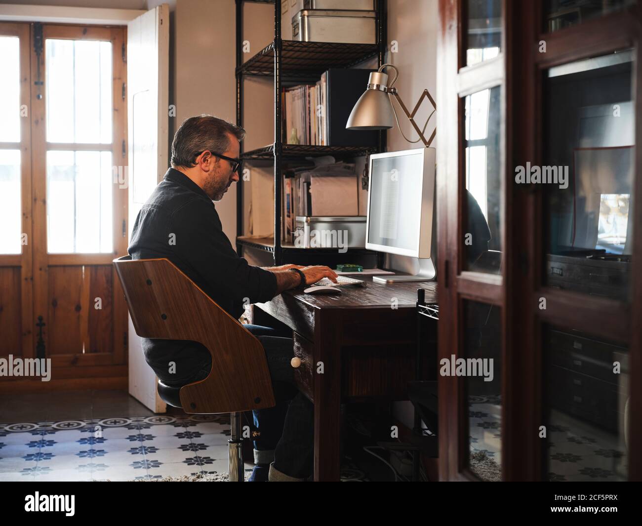 man working at home desk with computer via internet Stock Photo