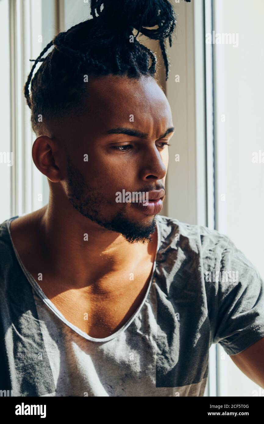 Thoughtful African American man with braids sitting at home on ...