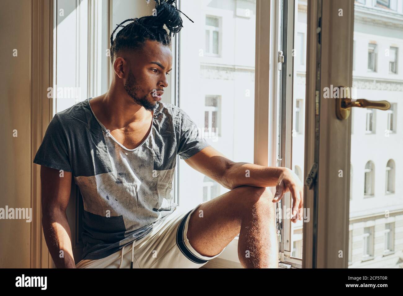 Thoughtful African American man with braids sitting at home on ...