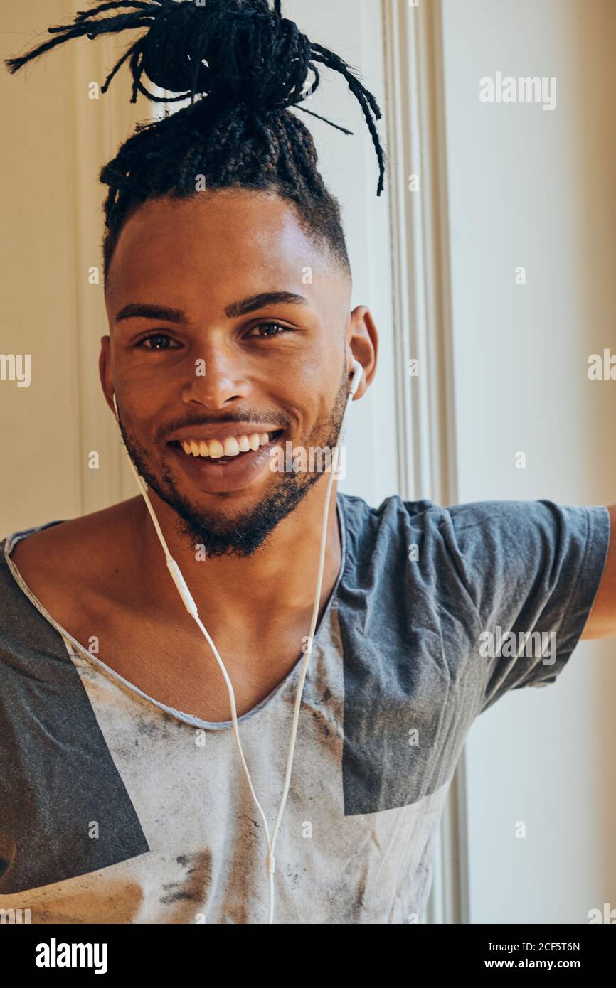 Side view of serious ethnic man with creative hairstyle listening to music  and leaning on window frame Stock Photo - Alamy