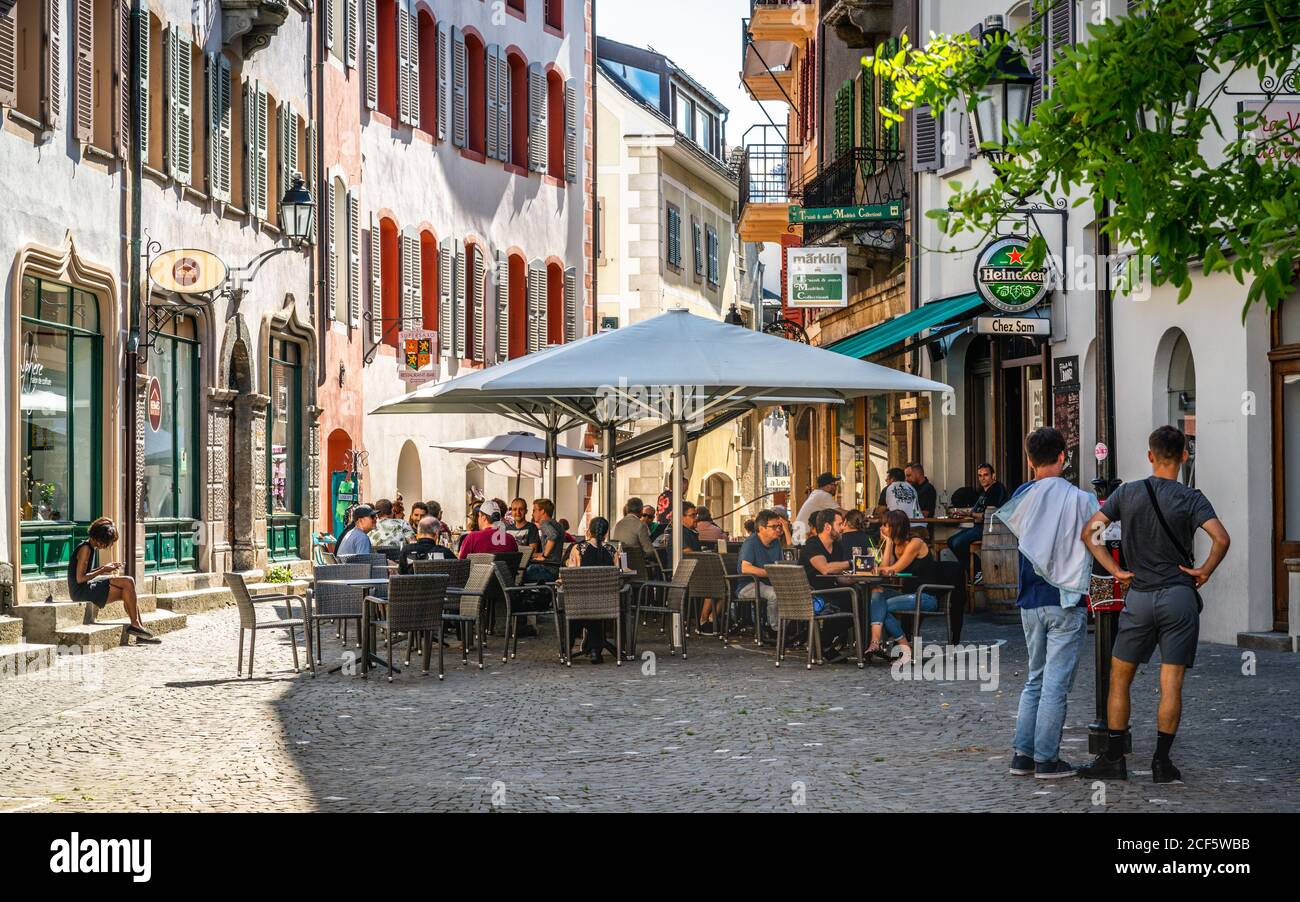 Sion Switzerland , 3 July 2020 : Bar terrace full of people on sunny summer day in pedestrian street of Sion old town Switzerland Stock Photo