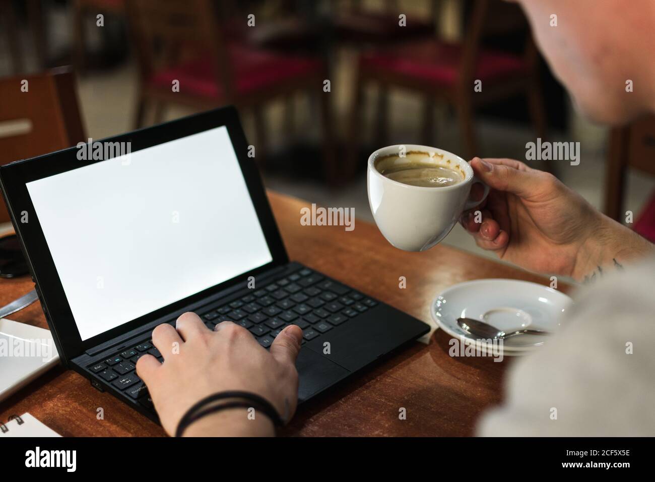 Freelancer sitting at cafe table and browsing laptop Stock Photo