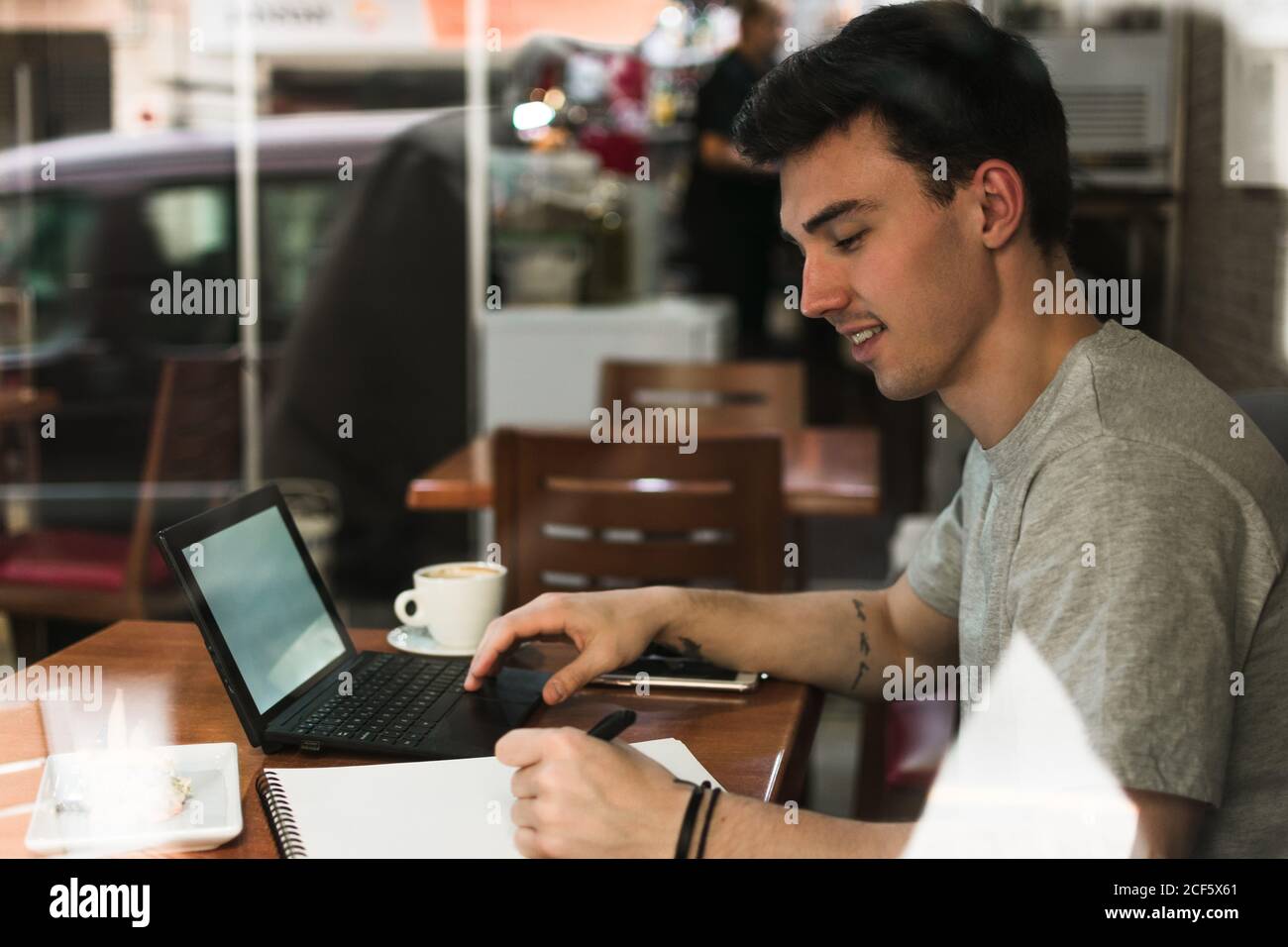 Freelancer sitting at cafe table and browsing laptop Stock Photo