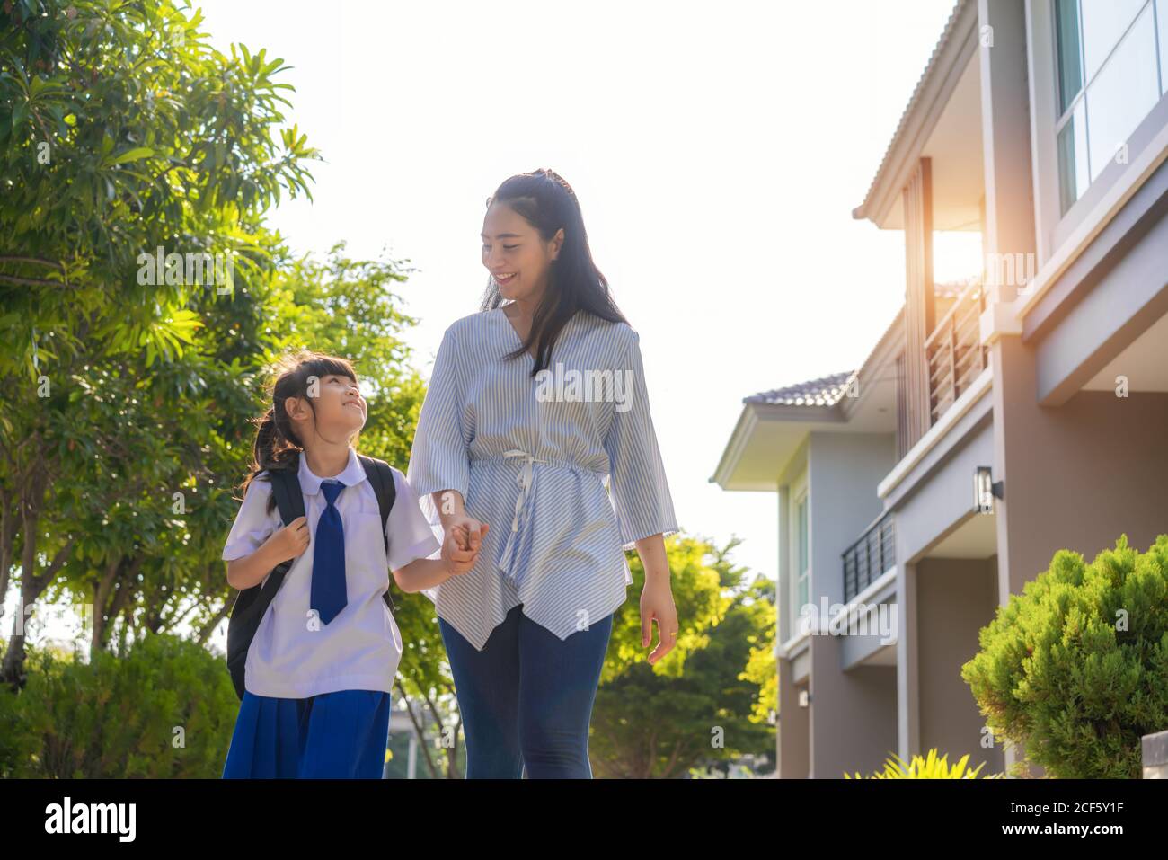 Happy Asian mother and daughter primary school student walking to school in the morning school routine for day in the life getting ready for school. Stock Photo