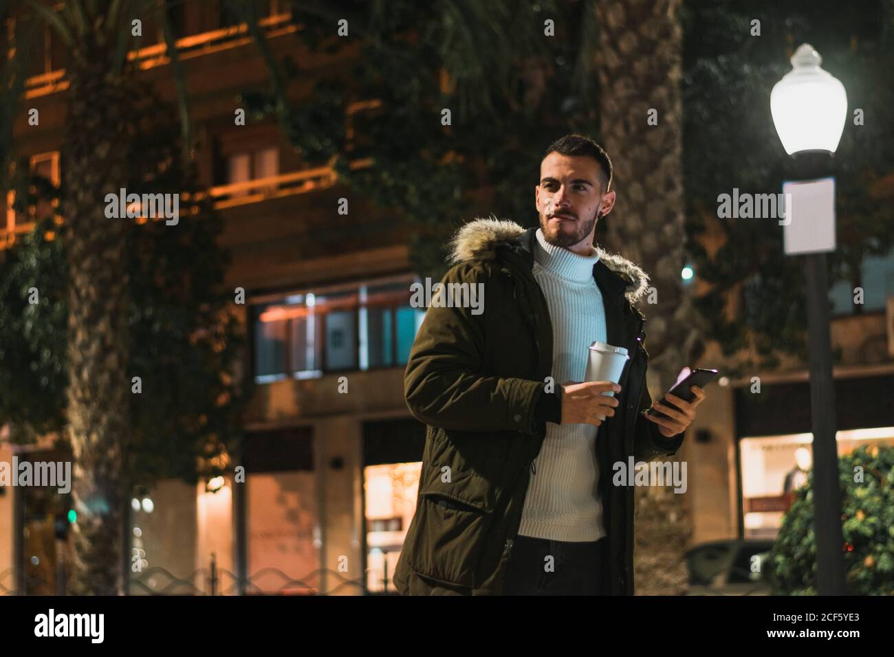 Smiling young man using smartphone in street Stock Photo