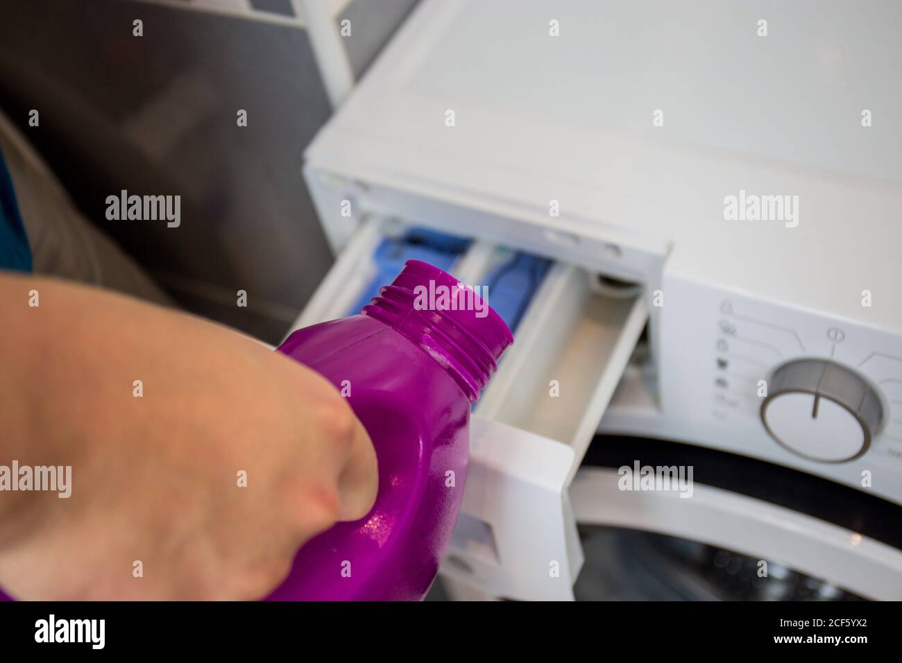 Washing machine, closeup, man pours laundry detergent or detergent