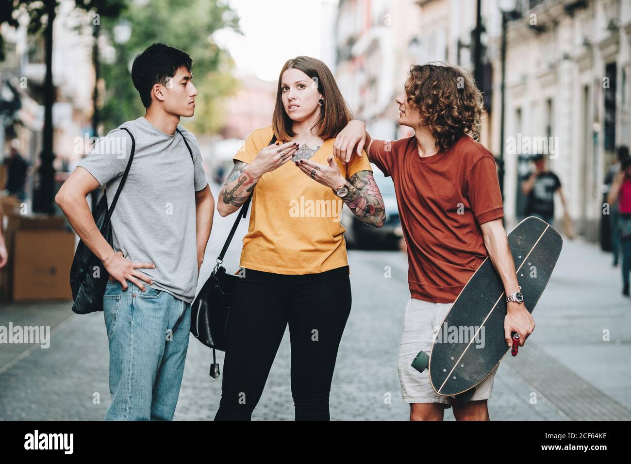 Multiethnic people in casual clothes talking while standing along urban street Stock Photo