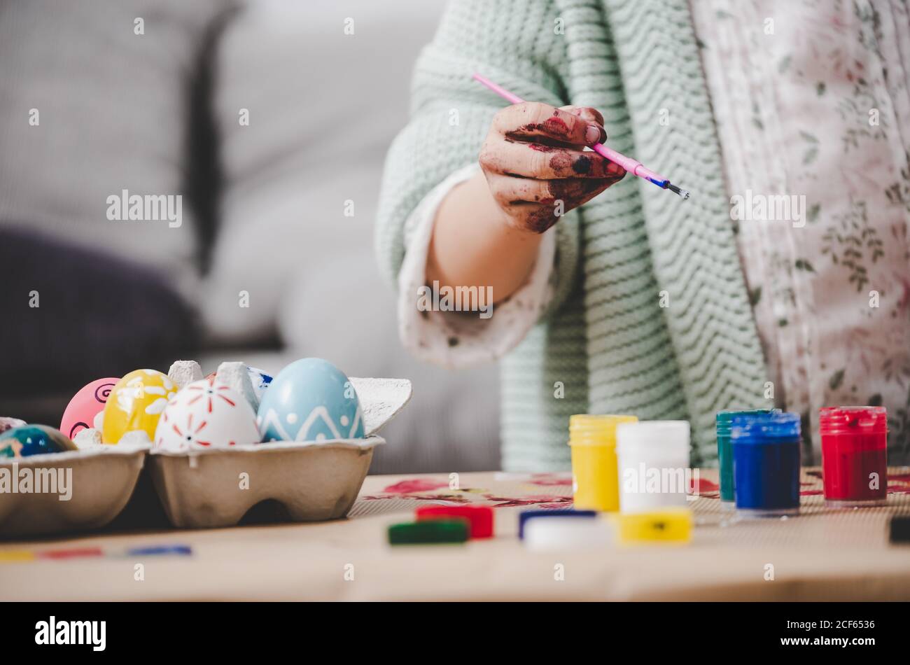Child with brush coloring chicken eggs at table Stock Photo